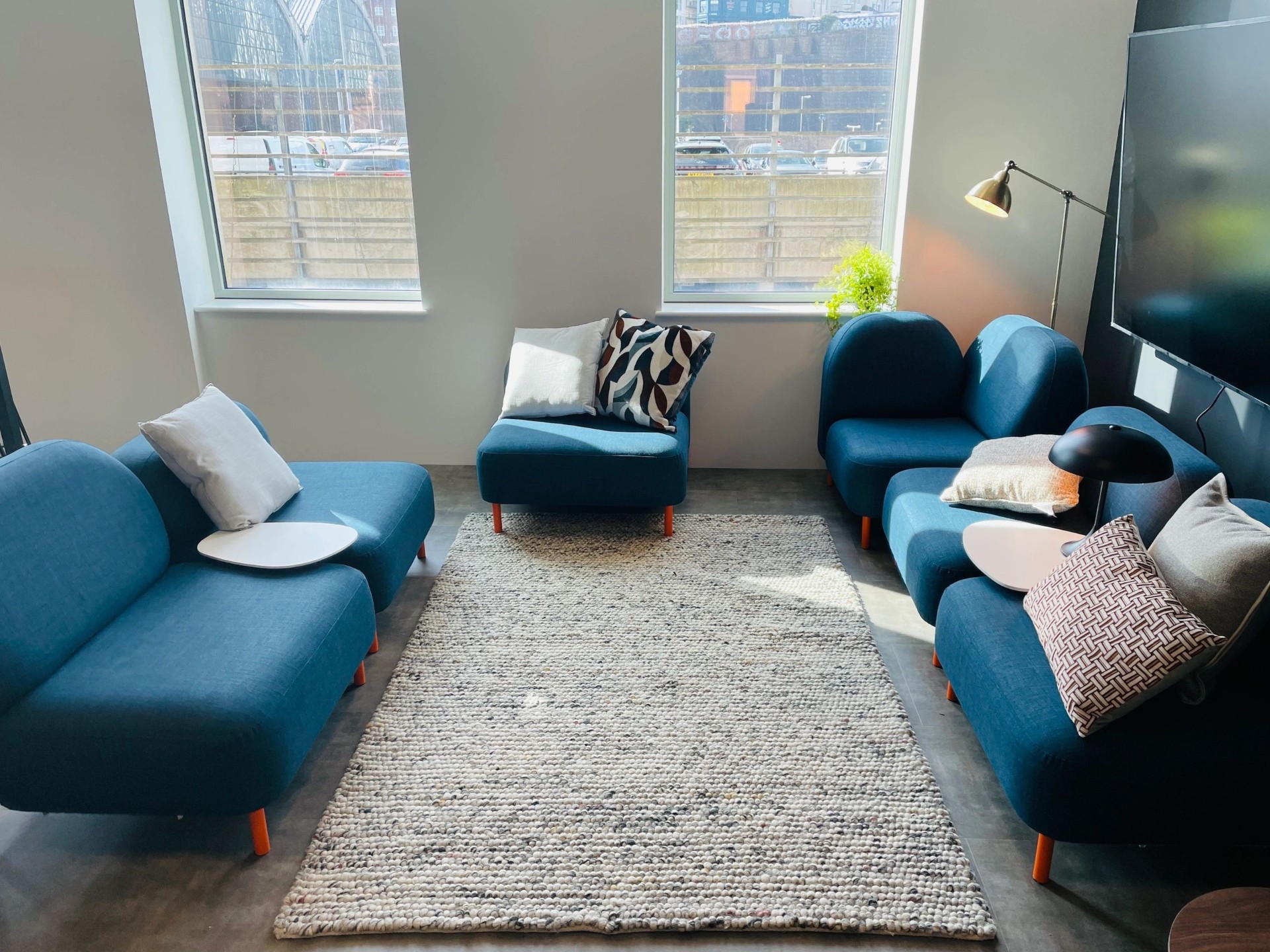Modular office breakout sofas in petrol-blue fabric arranged around a rug
