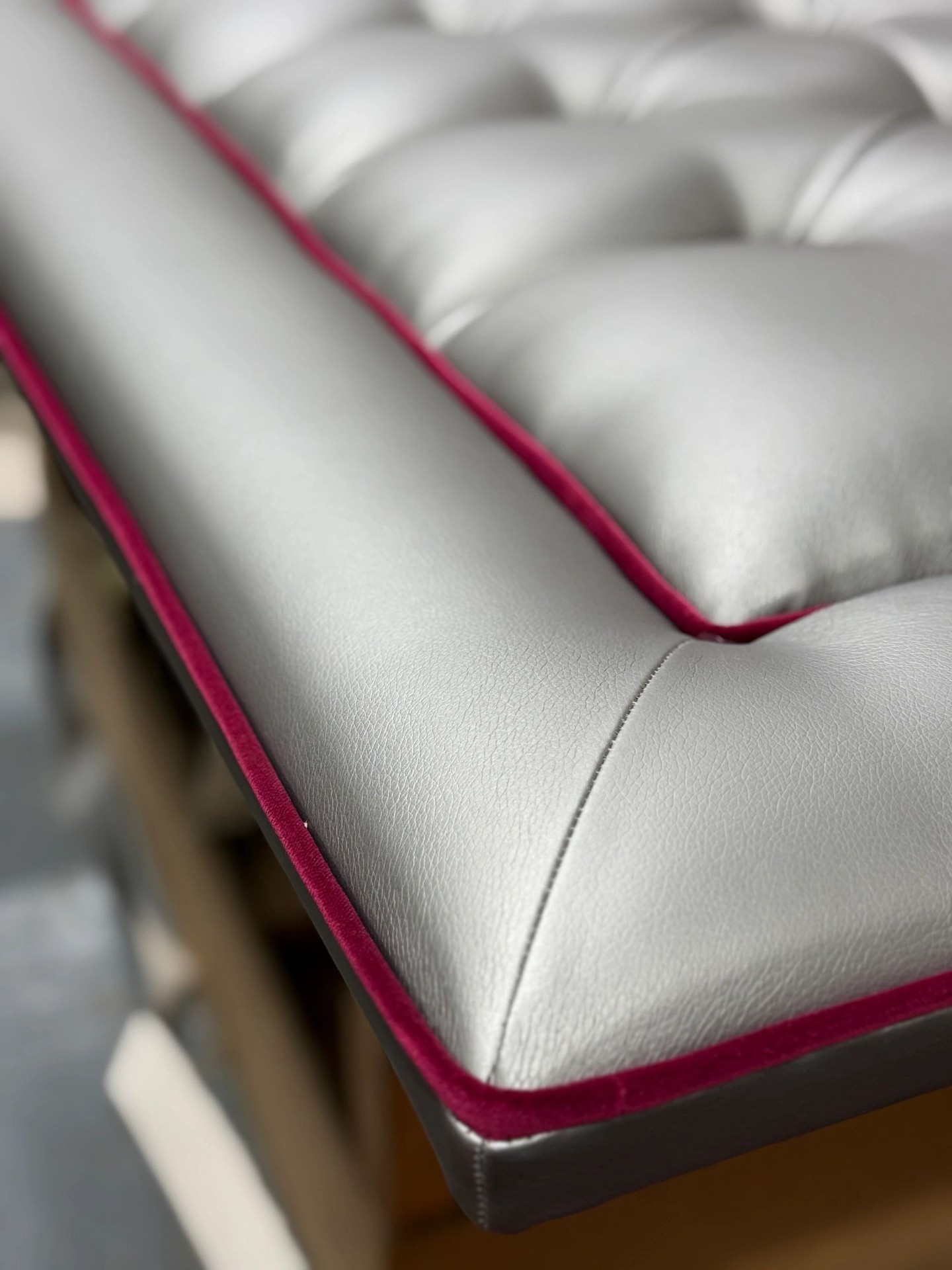 Reupholstery detail, silver leather buttoned seat with contrast red velvet piping