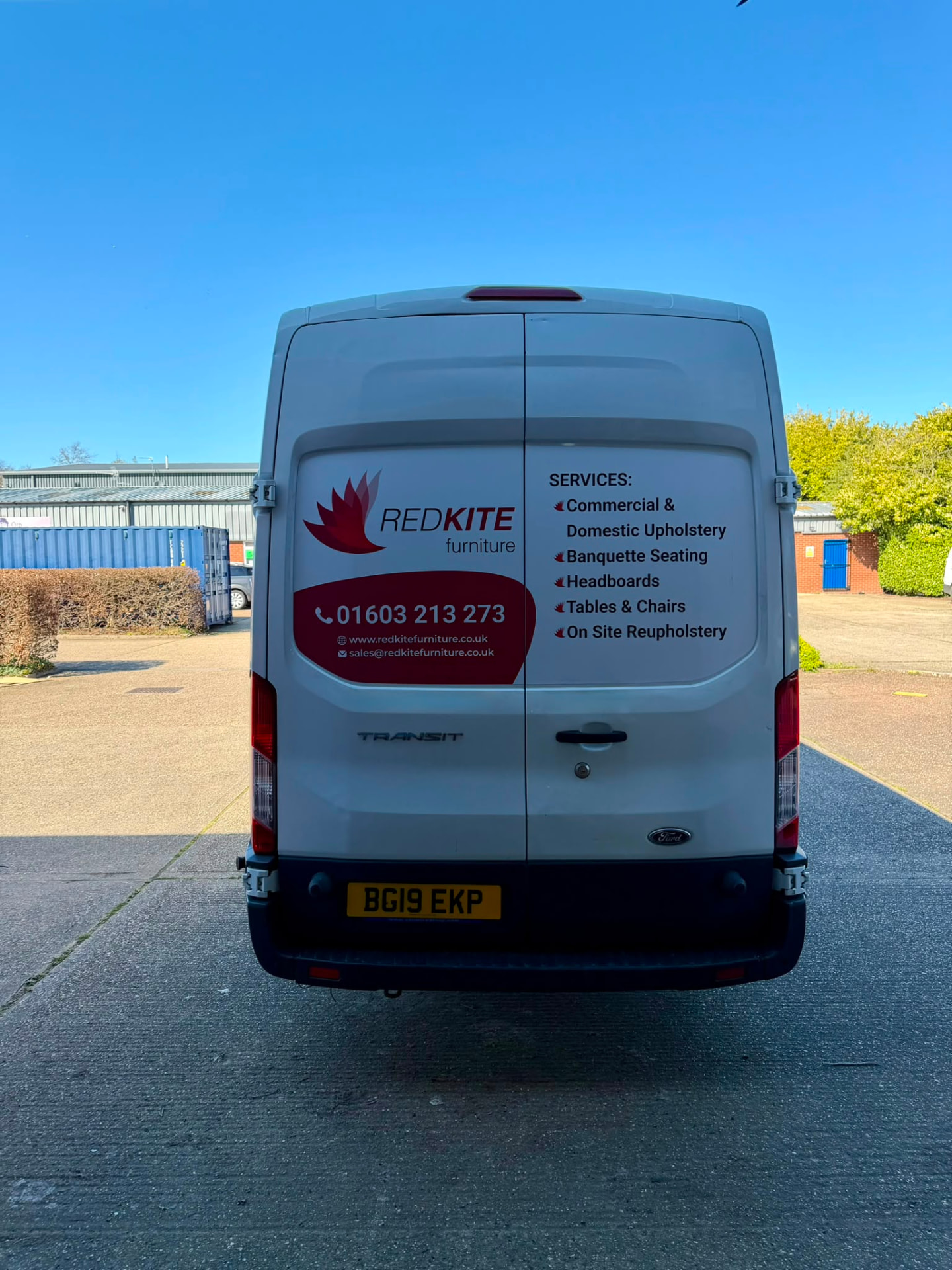 Rear of the Red Kite Furniture van listing services including banquette seating, headboards, tables and chairs and on-site reupholstery